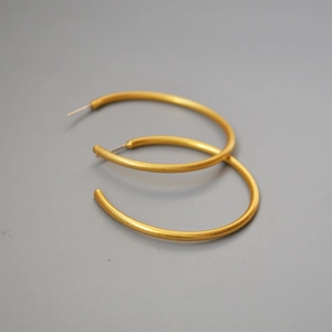 Close-up of golden matte brushed hoop earrings with elegant minimalist C-shape design