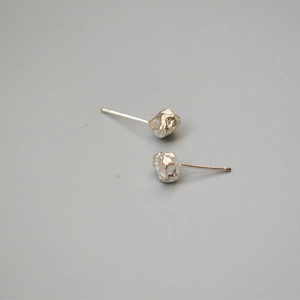 Detailed view of silver irregular lava rock texture stud earrings on grey background