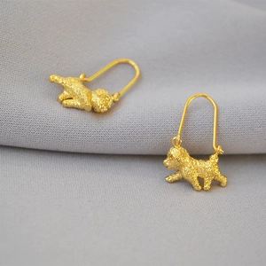 Detail of gold plated brass poodle earrings with a matte textured finish on grey fabric
