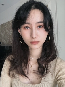 Close-up of gold bamboo texture hoop earrings with pearl necklace and letter J pendant