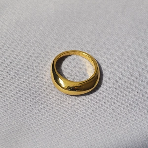 Nahaufnahme eines polierten Gold-Dome-Rings mit Spiegelglanz auf Strukturstoff