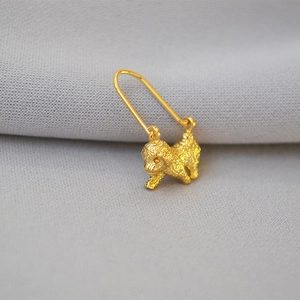 Detailed close-up of a gold-plated poodle dog earring with fine curly fur texture