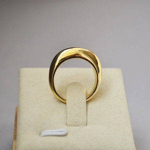 Nahaufnahme eines breiten polierten Goldmessingrings mit asymmetrischem Design