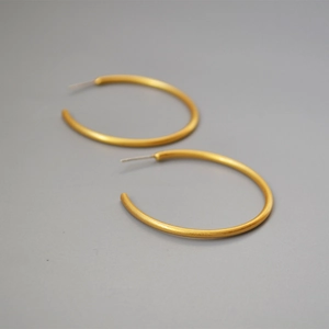 Detail view of gold-plated brass C-shape hoop earrings with matte brushed texture