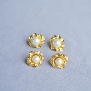 Orecchini a fiore dorati in argento 925 con perle bianche su sfondo viola tenue