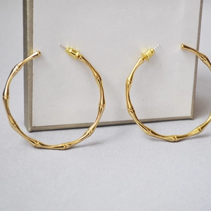 Detail shot of large gold bamboo textured hoop earrings with a polished metallic finish