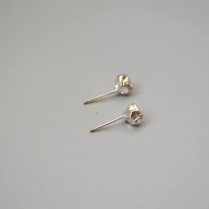 Macro detail of irregular silver lava rock texture stud earrings with a matte metallic finish
