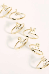 Close-up of gold plated initial rings with letter charms and single round zircon stone
