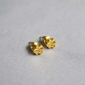 Detailed view of hammered gold stud earrings with irregular cloud texture on grey fabric