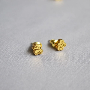 Macro shot of bear-shaped gold-plated stud earrings with unique hammered metal texture
