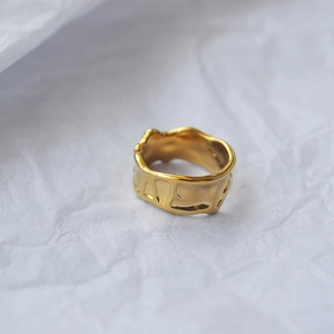 Makro-Detail des goldenen Lava-Rings mit LOVE-Prägung und unregelmäßigem Wellenrand