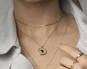 Detail of layered gold choker necklaces with paperclip chain and black stone pendant