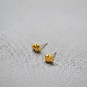 Close-up of irregular gold lava texture earrings with a hammered metallic finish