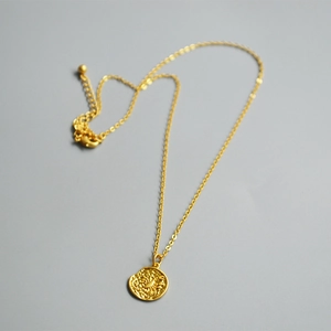 Detail of vintage gold coin pendant with zodiac relief and delicate curb chain