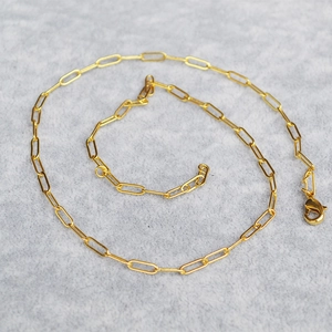 Close-up of a minimalist gold paperclip chain link with a classic lobster clasp closure