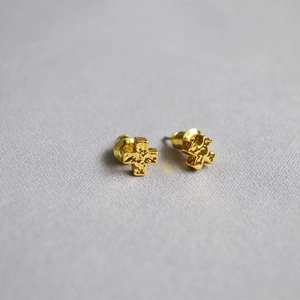 Detailed macro shot of golden cross earrings featuring a unique hammered texture finish