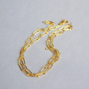 Detailed close-up of a golden paperclip chain necklace with a secure lobster clasp