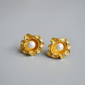 Dettaglio degli orecchini a fiore dorati con perle bianche e perni in argento 925