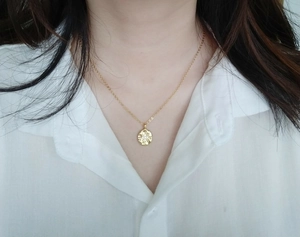 Detail of 18K gold plated coin necklace with star zircon on white shirt background
