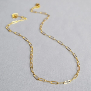 Close-up of golden paperclip chain necklace showing detailed metallic luster and texture