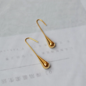 Detailed view of polished gold water drop earrings with elongated J-hook design