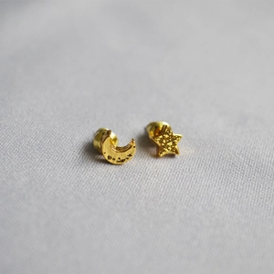 Close-up of gold-plated moon and star stud earrings with hammered metal texture