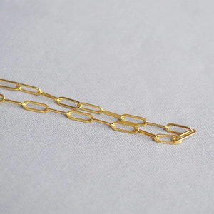 Macro detail of high-polished gold paperclip link chain necklace with smooth metal finish