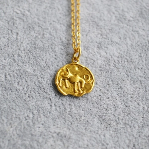 Detailed macro view of vintage gold coin pendant with embossed zodiac bull motif on chain