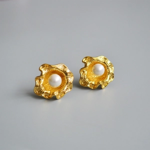 Dettaglio di orecchini dorati ondulati con perle bianche per un elegante design vintage