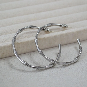 Detailed close-up of large polished bamboo-joint hoop earrings in silver finish