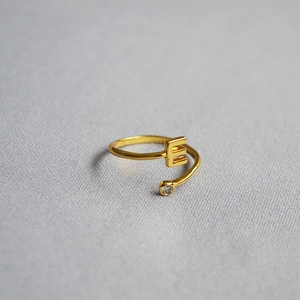 Macro shot of adjustable gold letter E ring with a sparkling clear cubic zirconia stone