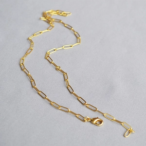Detailed view of polished 18K gold paperclip chain necklace with lobster clasp closure