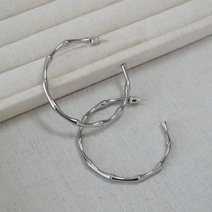 Macro shot of silver bamboo joint hoop earrings with polished metallic texture