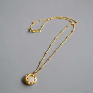 Détail du collier doré vintage avec pendentif en nacre baroque et chaîne à perles