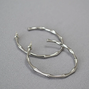 Detailed view of bamboo-joint style silver earrings with a high-polished mirror finish