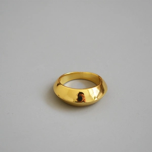 Detail view of wide gold brass ring featuring polished mirror finish and domed arc surface