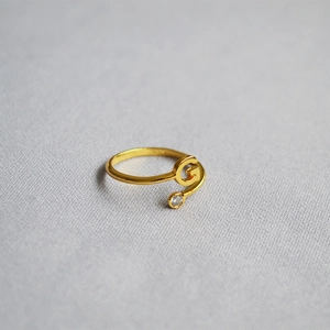 Close-up of golden adjustable ring featuring a letter G design with a sparkling crystal