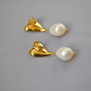 Détail de boucles d'oreilles perles baroques avec métal doré et clous en argent 925
