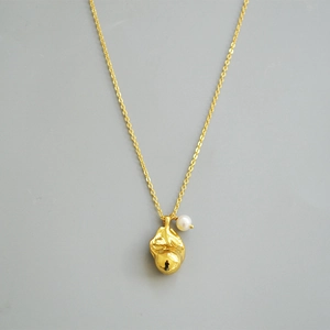 Macro detail of gold-plated pendant featuring lava texture and a small white pearl