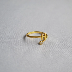 Macro detail of gold-plated open ring with letter H design and small zircon accent