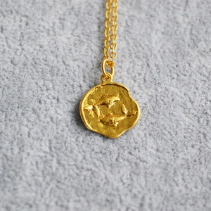 Macro shot of gold coin pendant with embossed fish pattern on textured background