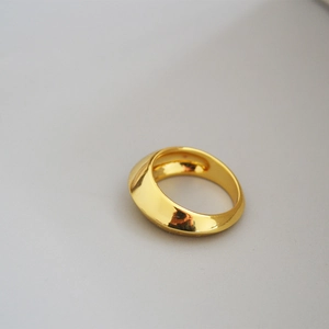 Close-up of a wide polished brass dome ring with a shiny golden mirror finish
