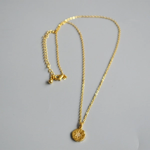Detail of 18K gold plated coin necklace featuring a zircon starburst pendant and lobster clasp
