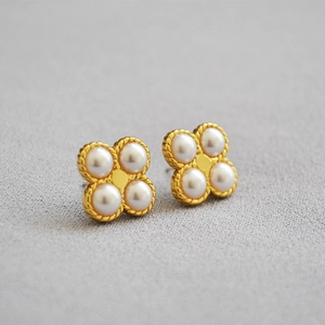 Macro shot of clover earrings with white pearls and twisted gold metal borders