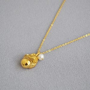 Detailed macro of gold-plated lava-shaped pendant with a single freshwater pearl
