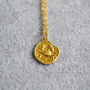 Macro view of a vintage golden coin pendant featuring a relief crab zodiac design