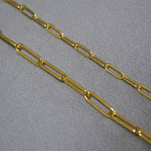 Macro shot of minimalist golden paperclip chain with shiny metallic texture and oval links