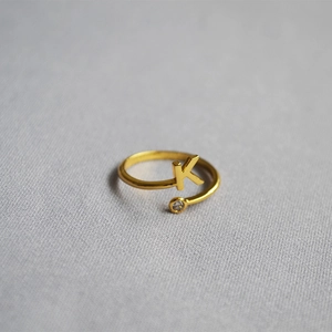 Macro detail of gold adjustable ring featuring a letter K charm and a sparkling zircon stone