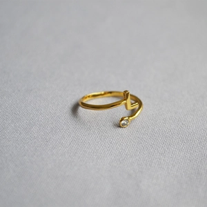 Macro shot of gold adjustable letter L ring with a sparkling zircon stone detail