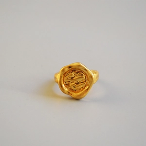 Détail d'une bague en laiton doré aux bords de lave et texture de vague abstraite